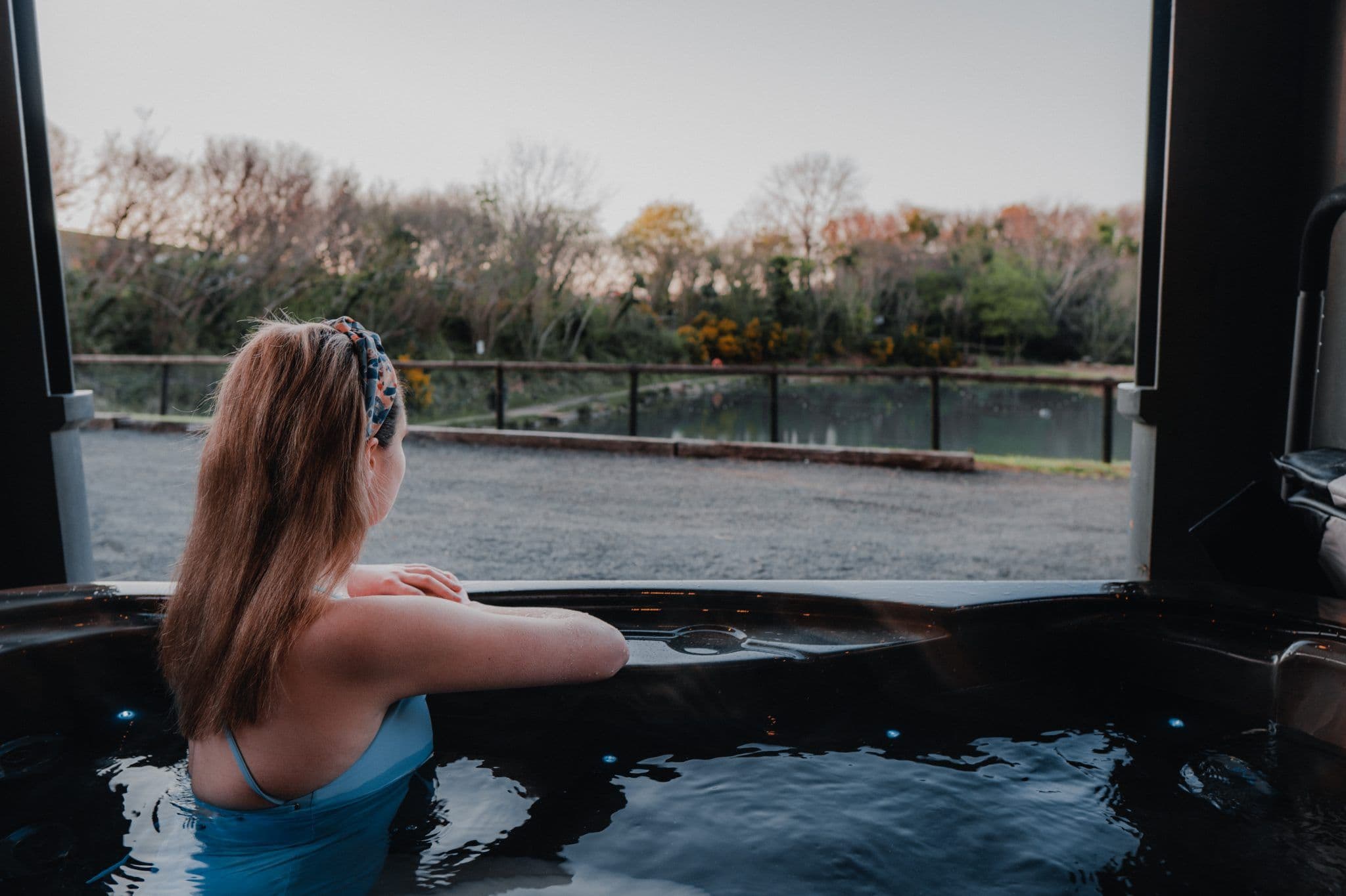 A guest relaxing in a private hot tub overlooking the trout lake at dusk